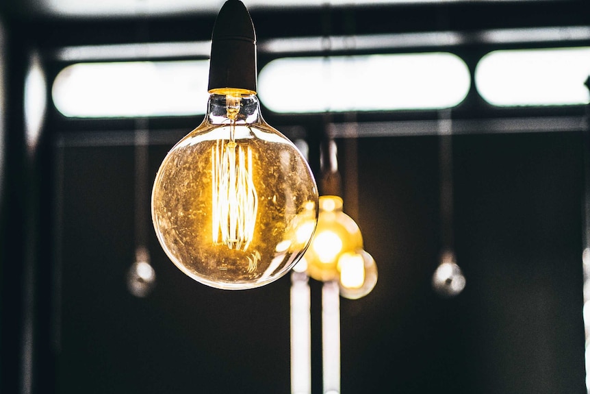 A close up of a large round lightbulb with a string of others behind it.