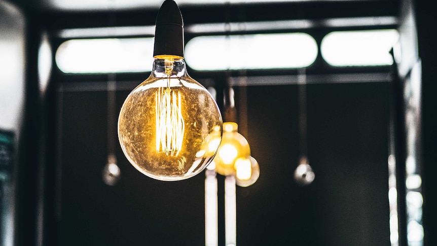 A close up of a large round lightbulb with a string of others behind it.