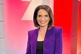 A woman in a purple suit smiling standing in front of a 7 News sign
