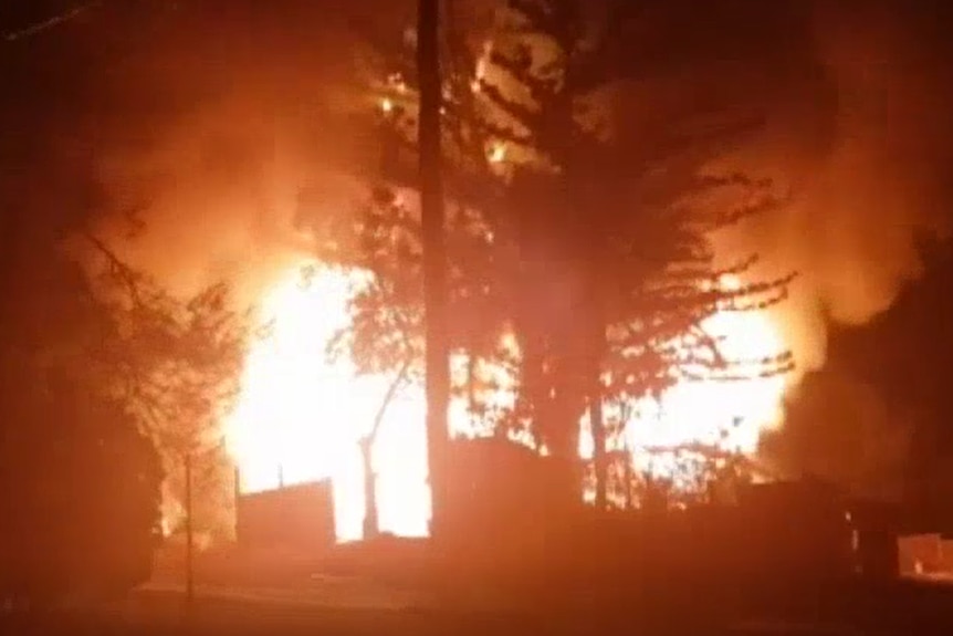 Fire engulfing a house at night.