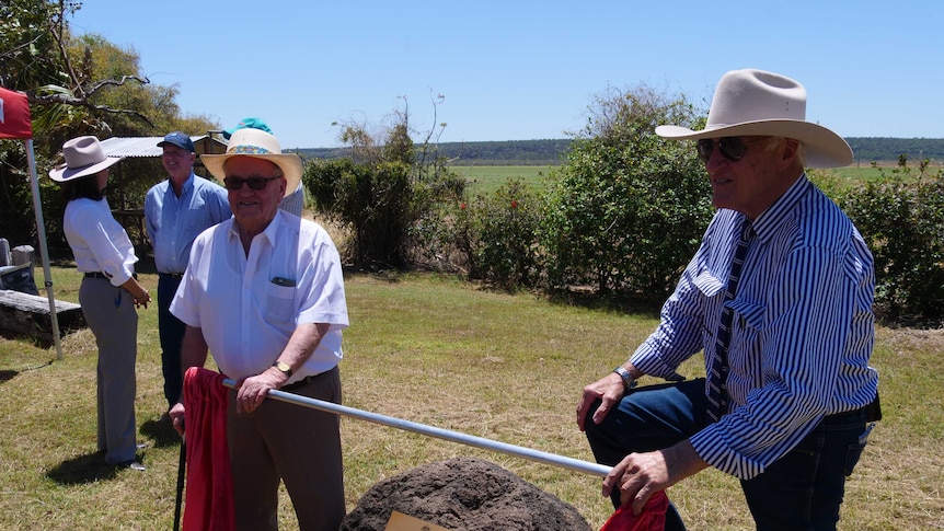 Two men wearing hats unveil a plague at an outdoor venue in Hughenden in western Queensland.
