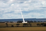 A rocket flies over farmland