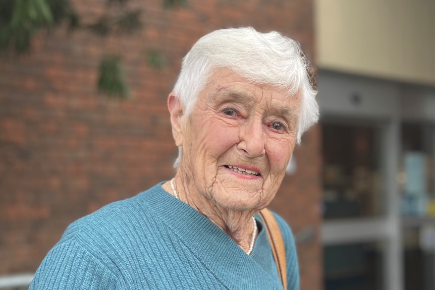 Betty smiles as she stands in front of a library building.