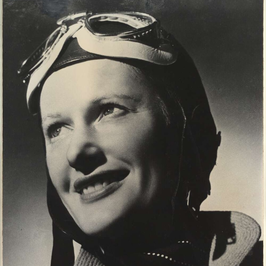 Black and white portrait photo of Nancy Bird Walton in her flight goggles and smiling