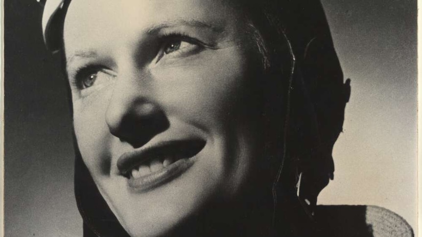 Black and white portrait photo of Nancy Bird Walton in her flight goggles and smiling