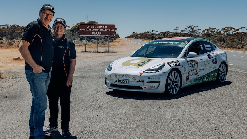 A husband and wife in front of a rally car on the remote Nullarbor.  