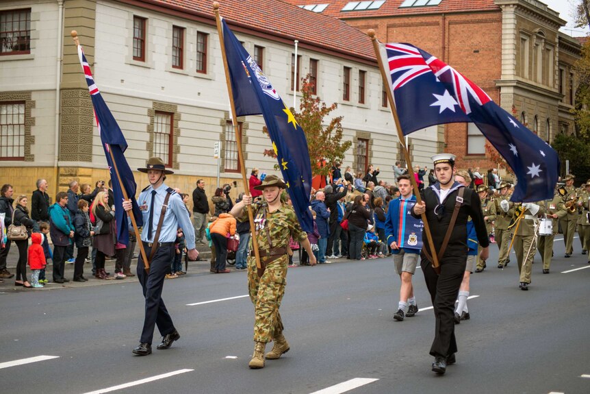 Defence force cadets bearing flags lead the Hobart Anzac march.
