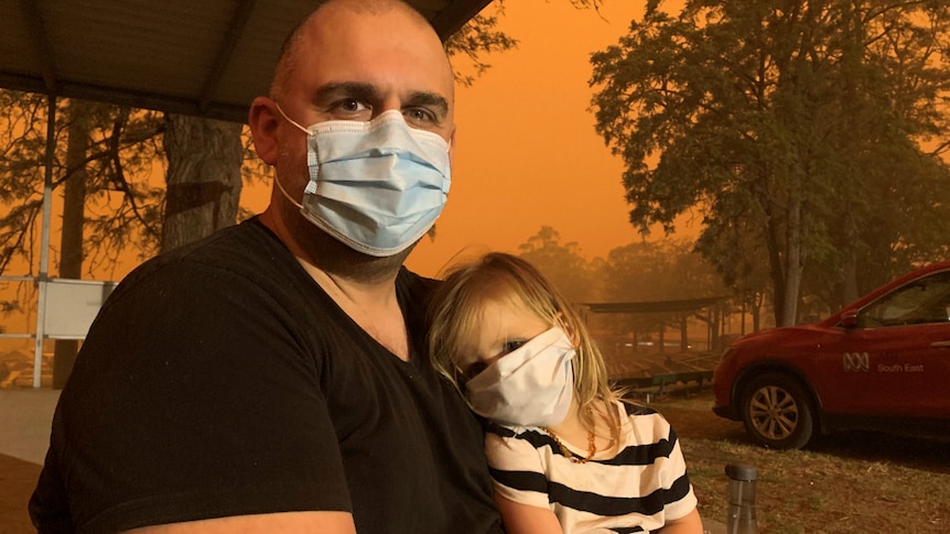 Mark and his daughter Charlie from Melbourne wear face masks at the evacuation centre in Bega.