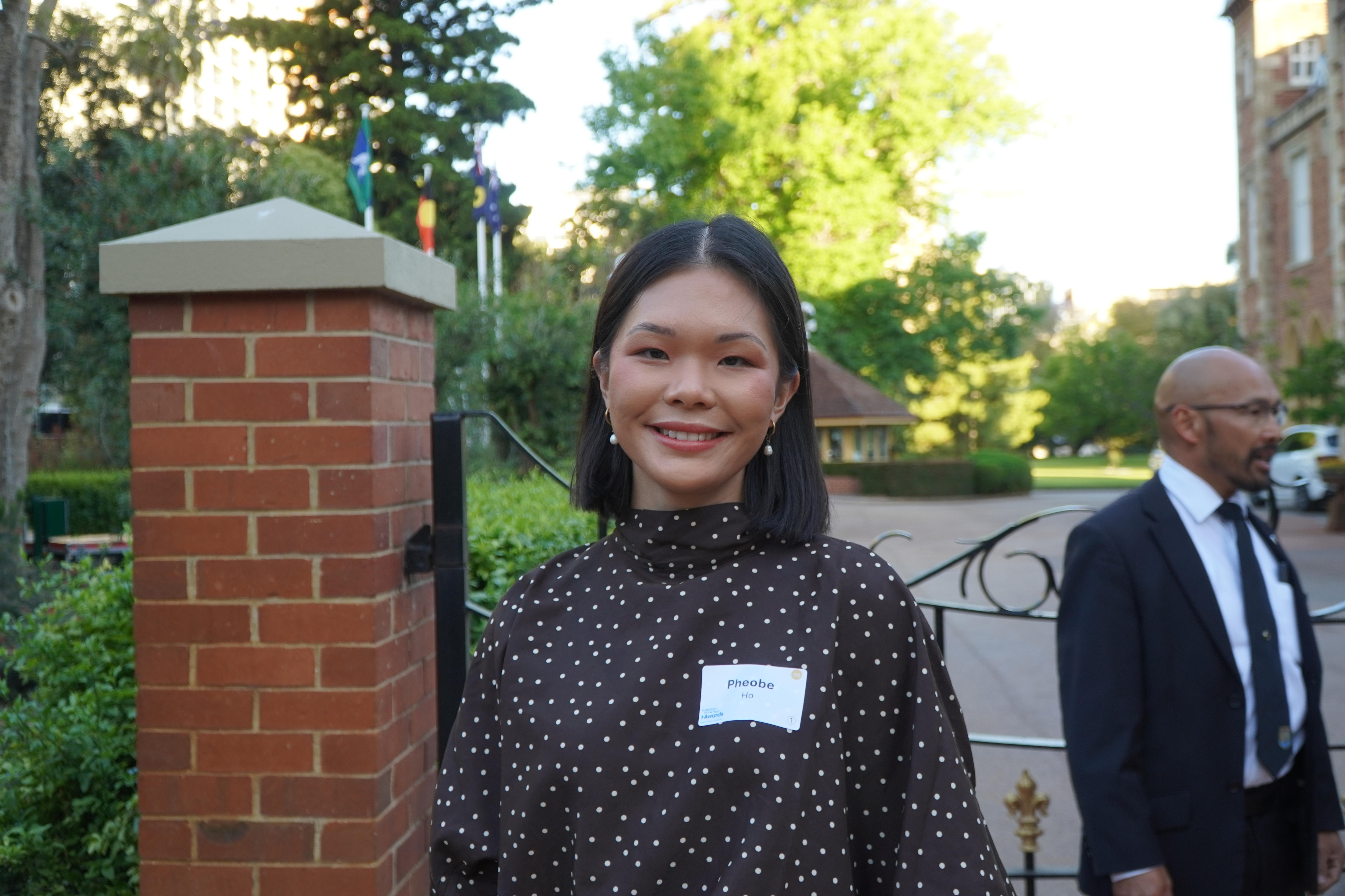 Phoebe Ho stands smiling outside a gate.