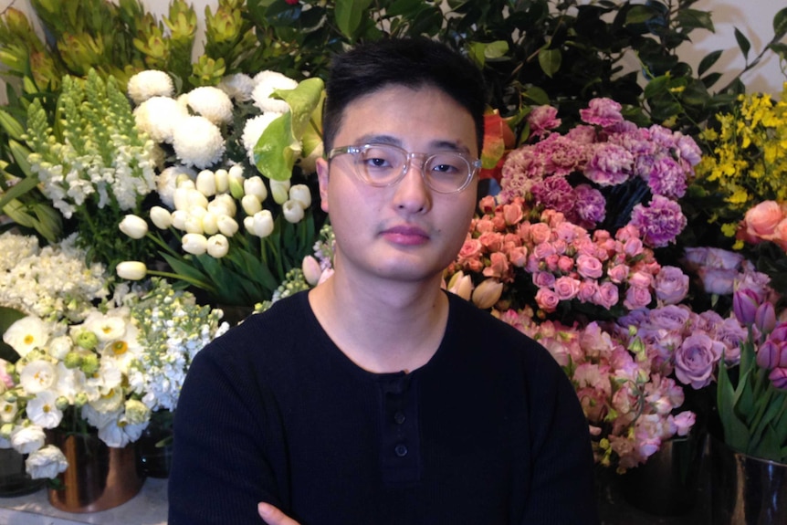 Florist employee Huey Tian Jin in front of a bunch of flowers.