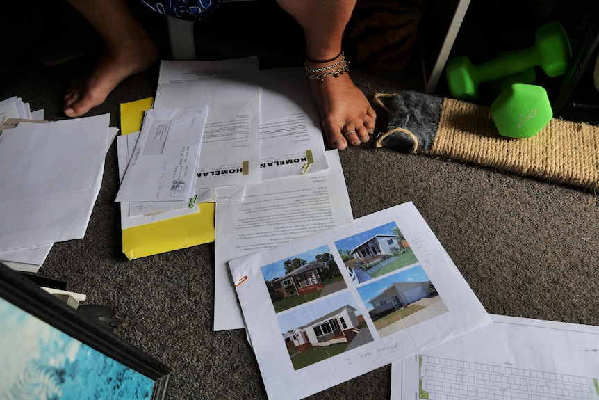 Letters scattered on the floor including photos of four designs of houses