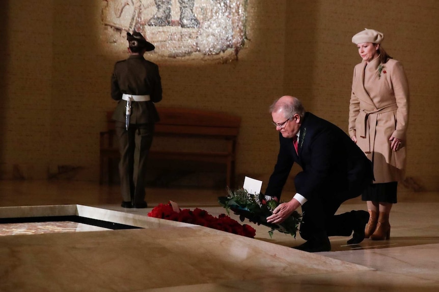 Scott Morrison in a suit with his wife next to him lays a wreath at the tomb of the unknown soldier