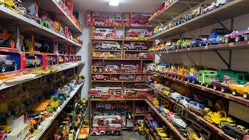 Shelves full of miniature trucks line the walls of a narrow storage room