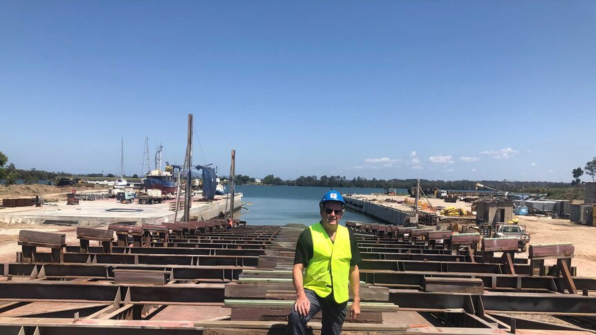 Ross Roberts stands at a ship building yard