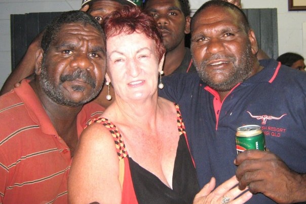 White woman stands front centre to pose for a photo with her Indigenous customers who are smiling and holding beers