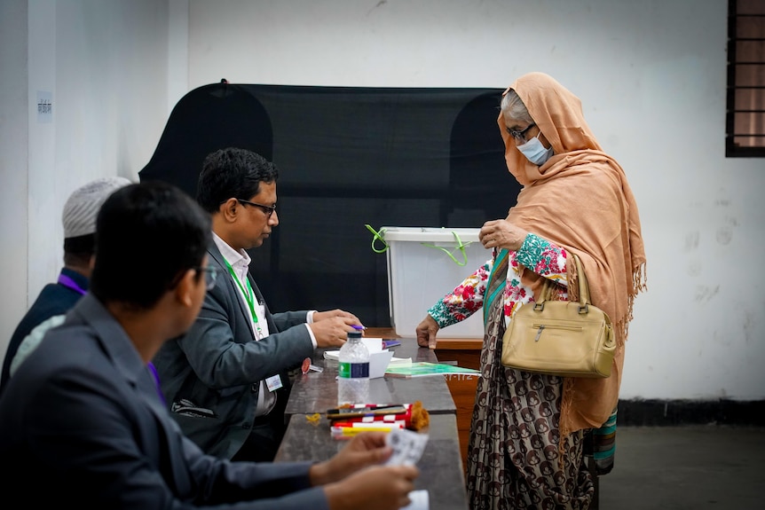 A woman in an orange veil casts her vote 