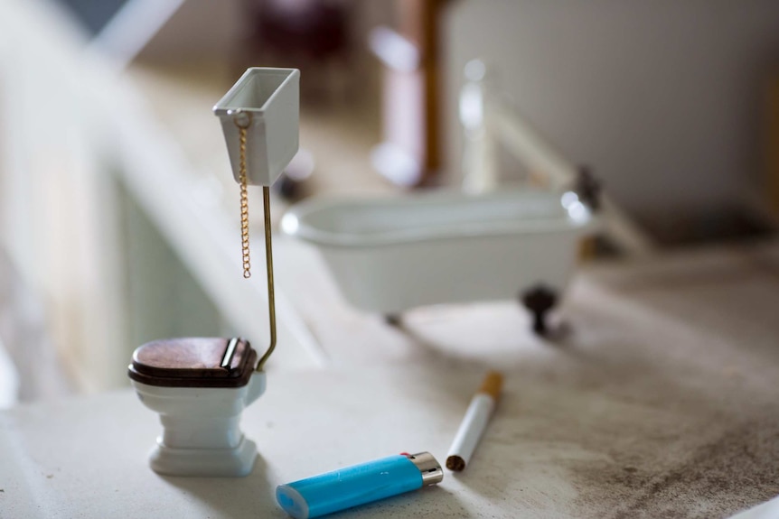 A cigarette and lighter rest amongst miniature furniture