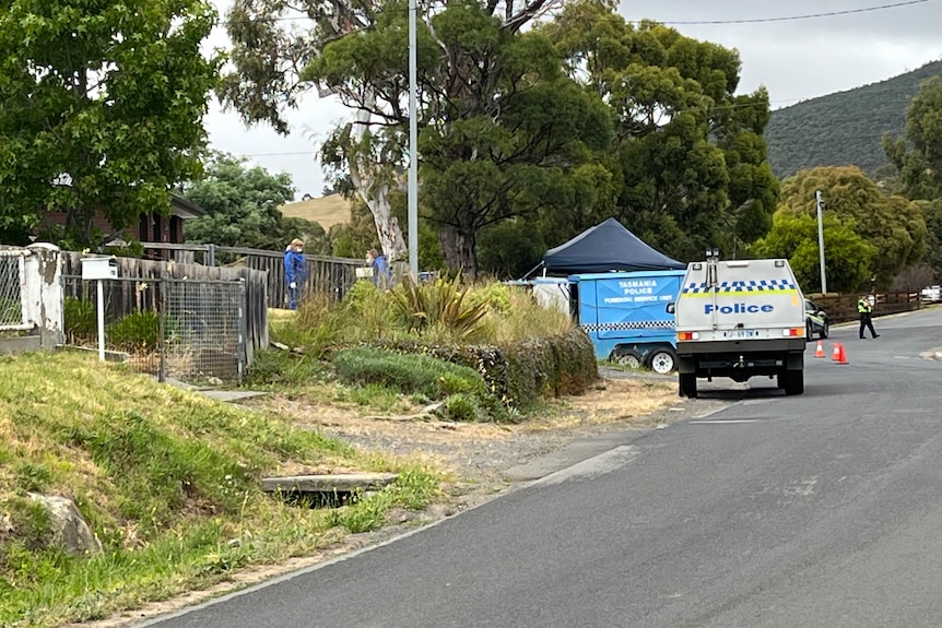 Forensic police walk at a property in Granton. Police vehicles are parked on the side of the road.