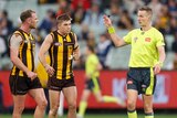 Tom Mitchell and Hawthorn players talk to an umpire
