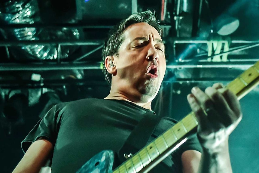 Jon Toogood, frontman of Shihad, plays a guitar on stage during a concert.