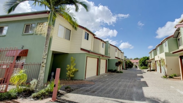 A block of green and cream apartments with blue sky in the background.