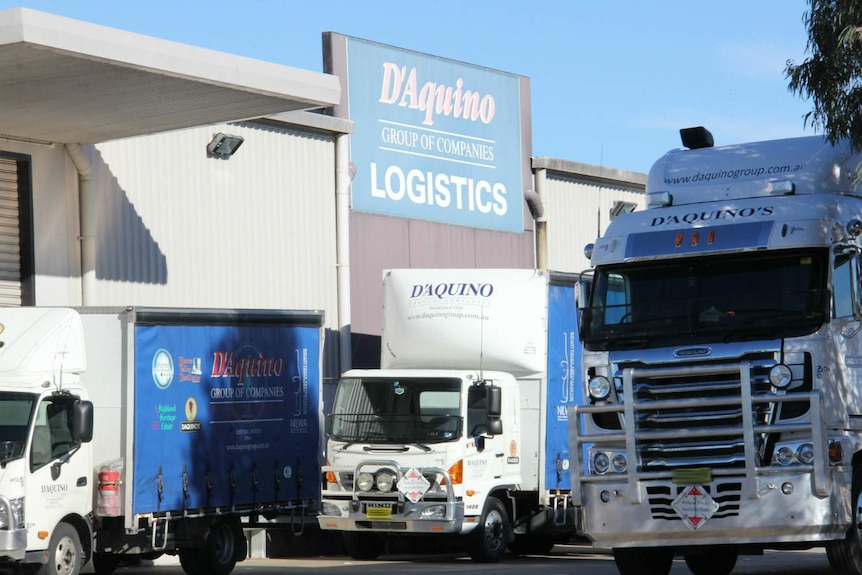 Several large trucks outside a warehouse.