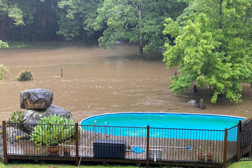 rising floodwaters in the background with a pool in the foreground