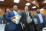 Three suited men hold budget document