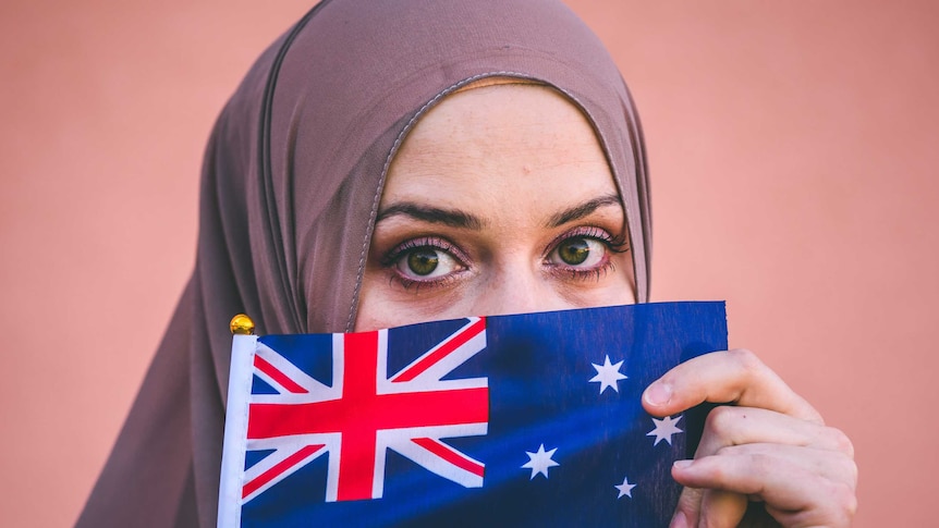 Muslim woman in hijab holds flag of Australia.