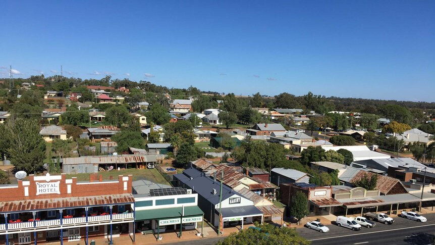 Aerial view of a country town with rusted tin roofs, roads and vehicles.