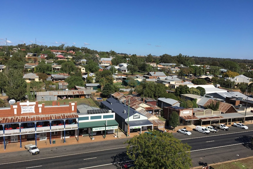 Aerial view of a country town with rusted tin roofs, roads and vehicles.