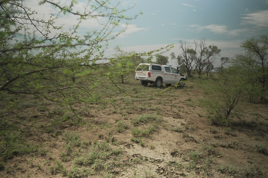 A four-wheel drive parked in rugged scrubland.