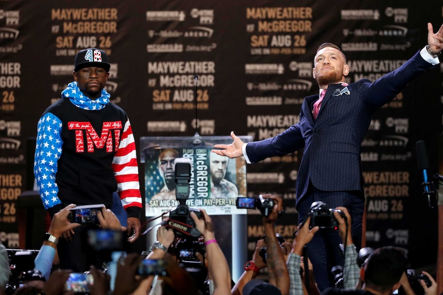 Floyd Mayweather looks ahead while Conor McGregor looks dramatically to the heavens at their press conference.