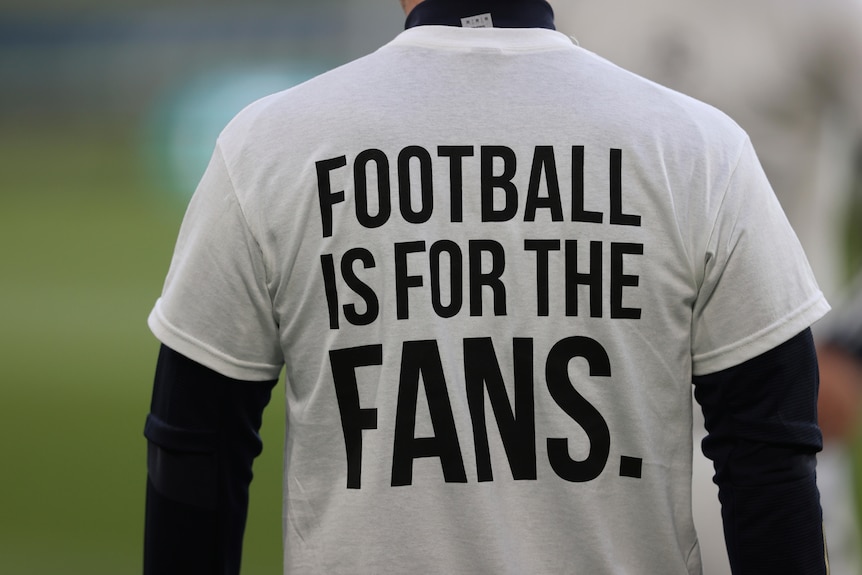 A footballer wears a t-shirt with a slogan while warming up before a Premier League game