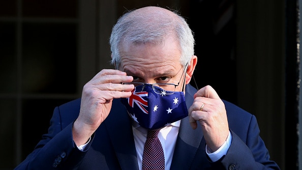 Prime Minister Scott Morrison adjusts his Australian flag mask at a media conference. 