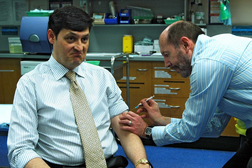 A man getting vaccinated by a doctor