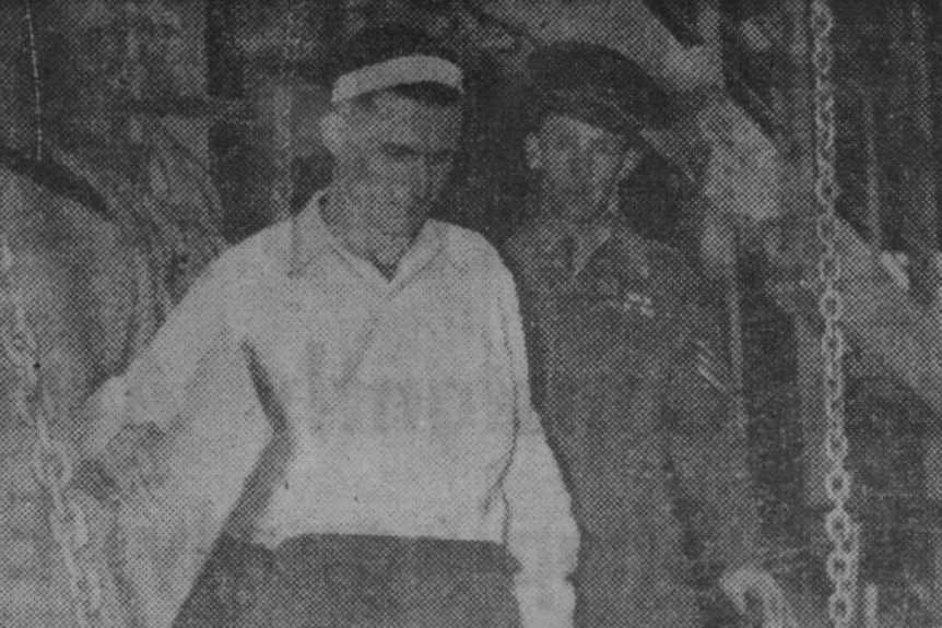 A black and white photo of a man being escorted off a boat by a man in uniform.