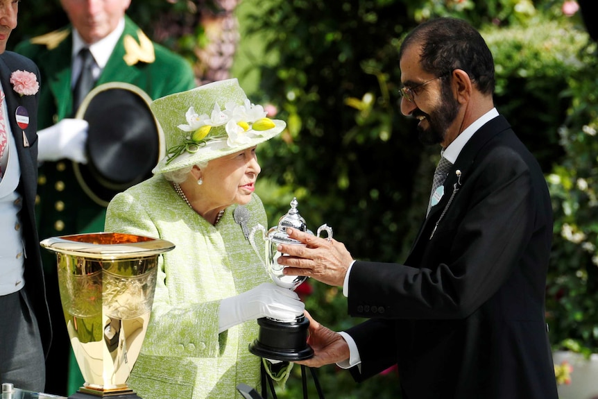 Queen Elizabeth hands a trophy to Dubai's ruler Sheikh Mohammed bin Rashid al-Maktoum