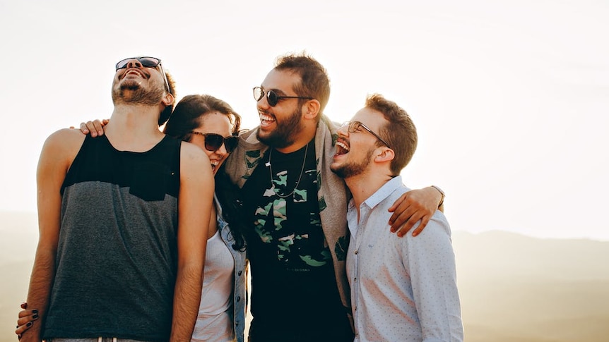 A group of happy people surrounded by sunlight to depict how to find joy during the draining holiday season.