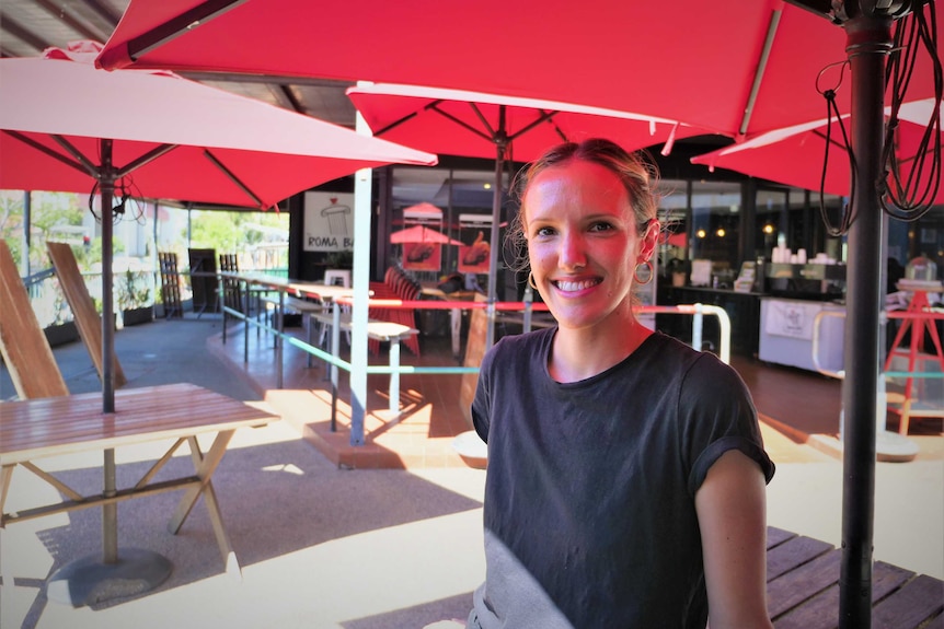 Phoebe sitting outside under red cafe umbrellas outside the Roma Bar on Cavenagh St in Darwin NT