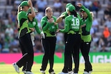 An excited cricket smiles as her teammates surround her to celebrate.