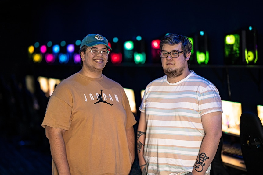 Dean Baron (right) with his friend, Jai, standing in front of neon computer lights.