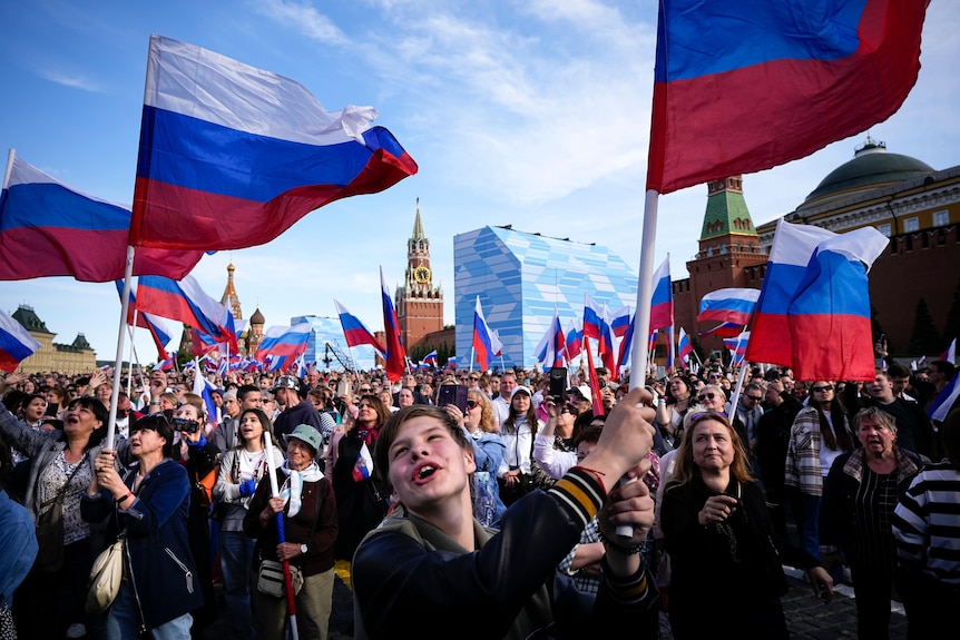 Thousands of people wave Russian national flags as they gather on Red Square.
