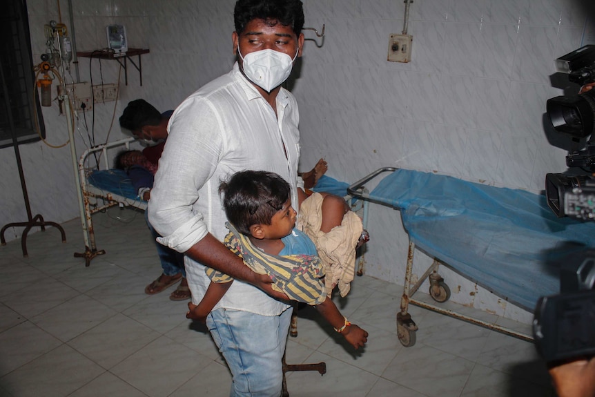 A young patient is carried by a man at the district government hospital in Eluru