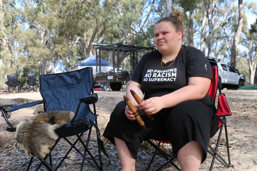 Georgia, with her possum pelt by her side, looking into the distance.