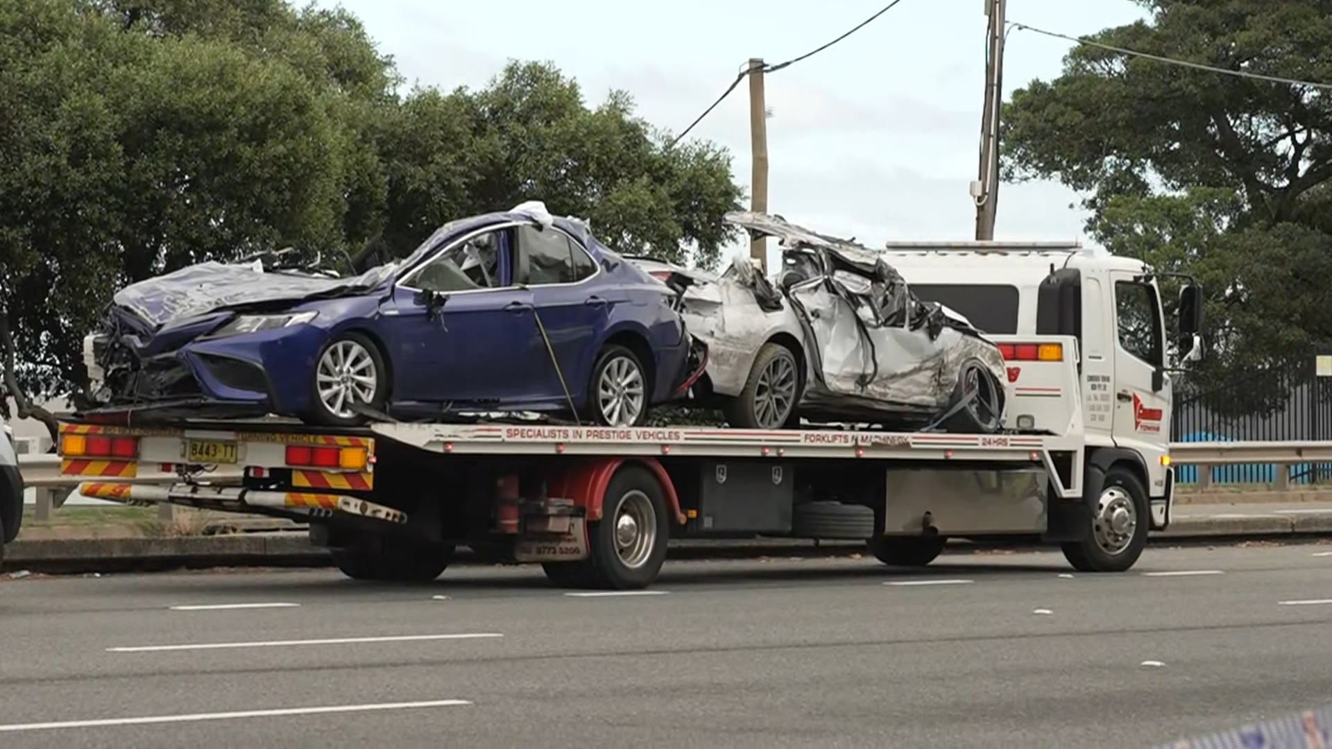 Two wrecked cars on the back of a tow truck.