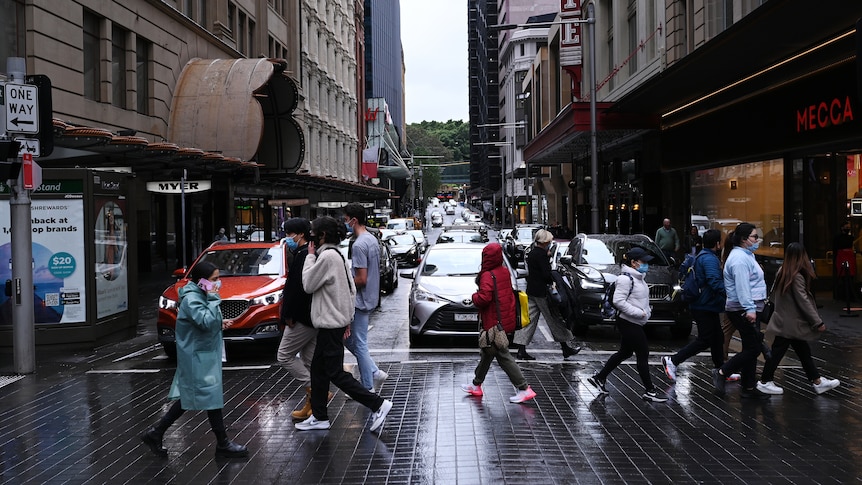A group of people cross a pedestrian crossing in Sydney CBD. 
