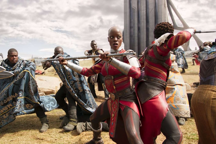 Still image from 2018 film Black Panther of Florence Kasumba and Lupita Nyong'o surrounded by enemies.