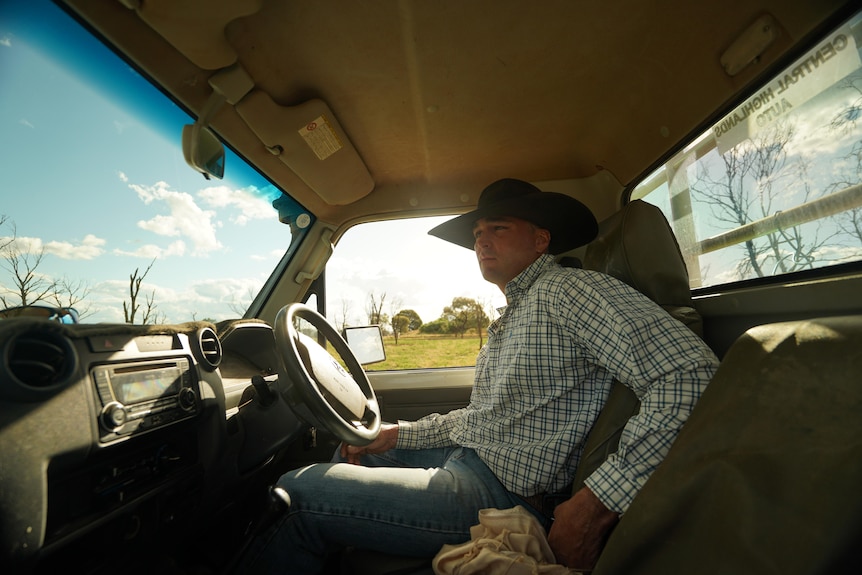 Man wearing hat sitting inside a cut looking out of front window