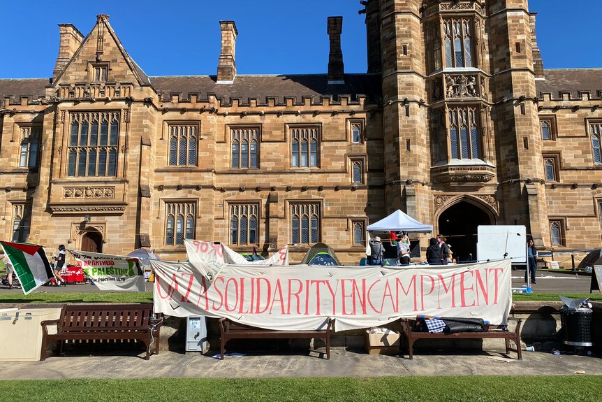 A banner reading 'Gaza solidarity encampment' in front of a historic building at Sydney University